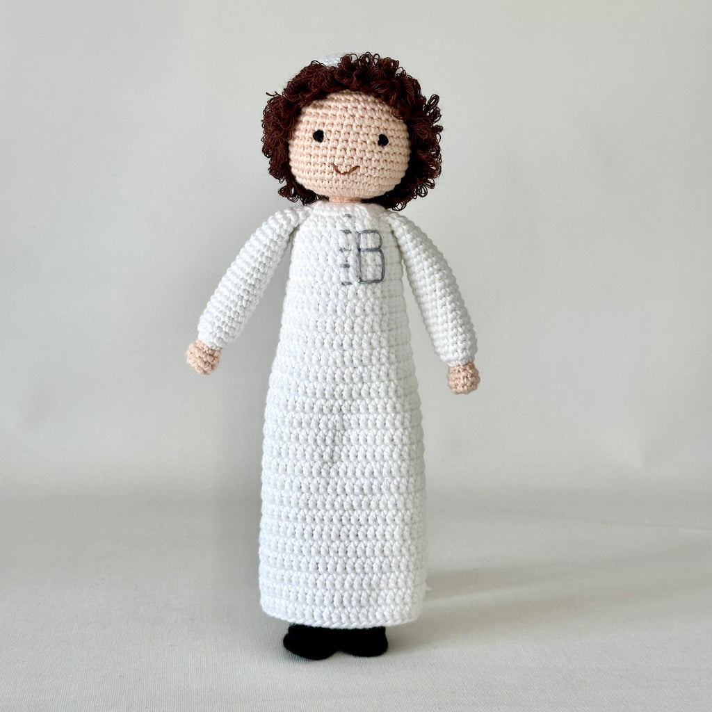 Crocheted doll with a white dress on a plain background