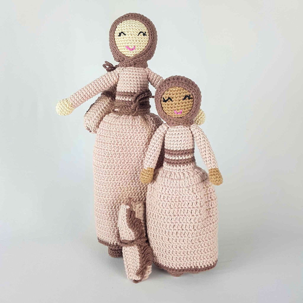 Muslim Hijab Doll with matching prayer mat. The two dolls are wearing a dust pink dress and brown hijab. The large doll has a light skin tone and the small doll has a dark skin tone.