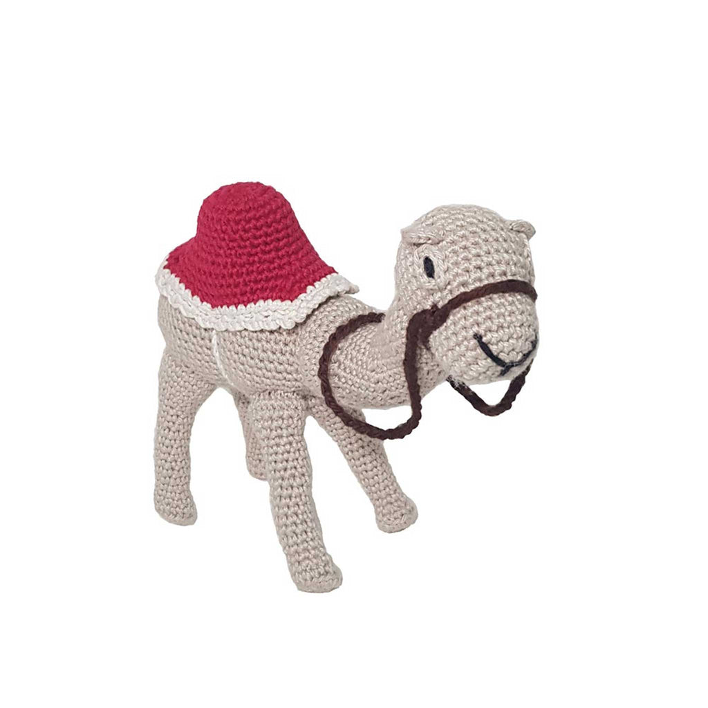 alt="handmade beige crochet camel standing with red saddle and brown leash attached to the nose"